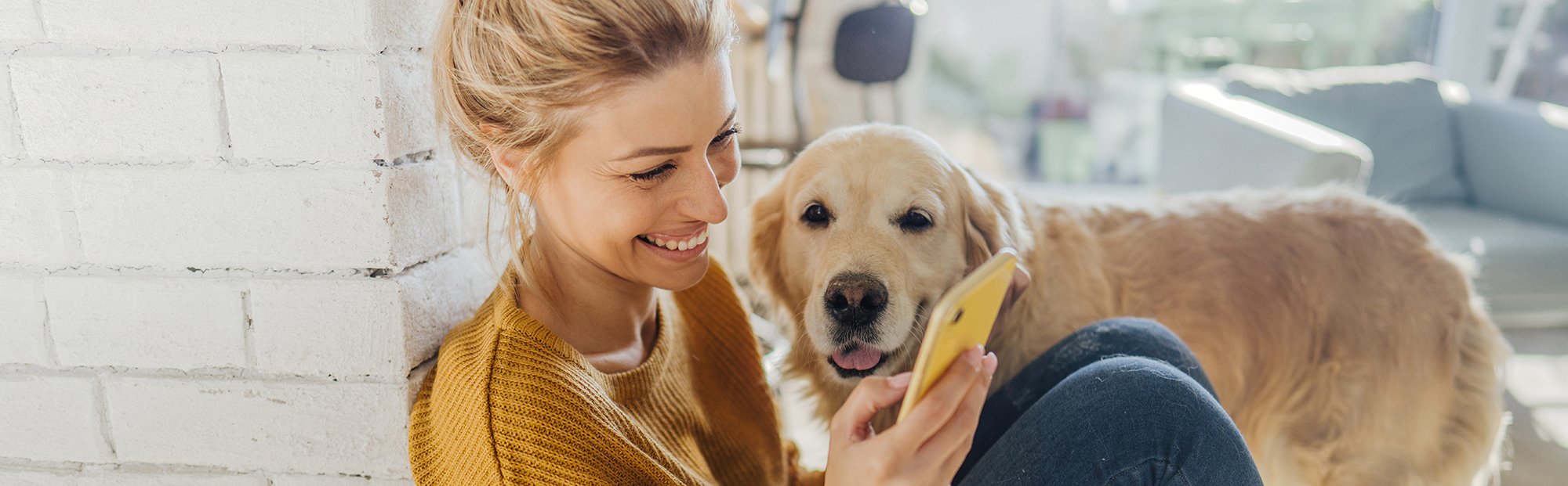 Young Woman Sitting on Floor with Phone and Dog