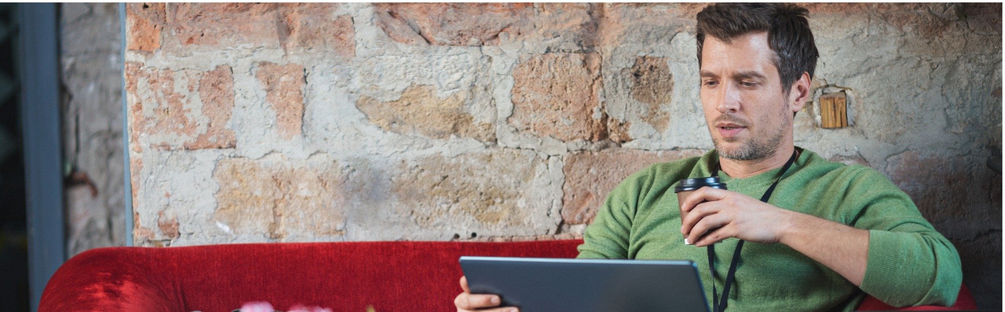 Man Using Tablet and Cellphone on Red Sofa