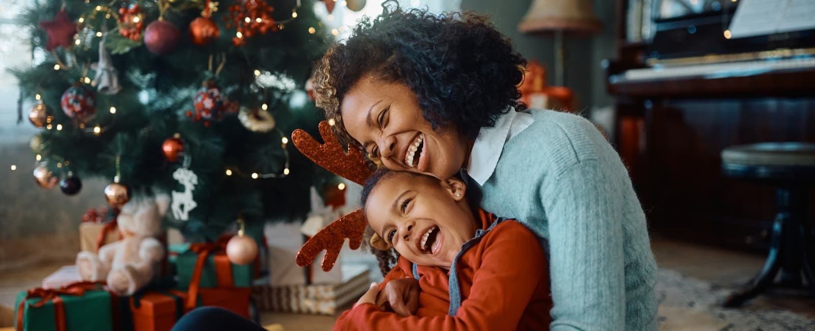 Woman and Son Smiling on Floor Near Christmas Tree